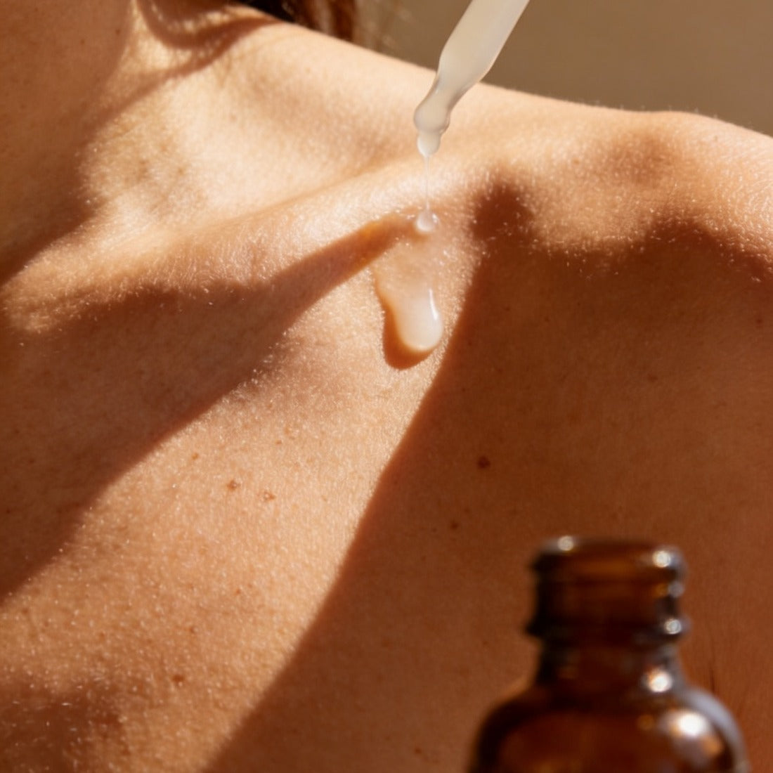 Silk Melt Serum plumping hyaluronic serum applied to bronzed clavicle with sun-shadow pattern