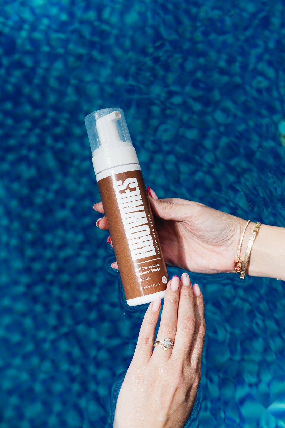 Brownies Coconut Fudge self-tan mousse held above pool water