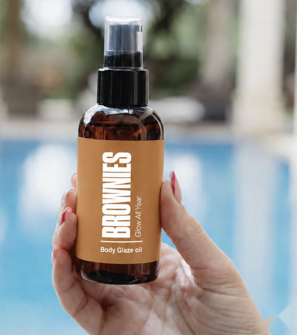 Body Glaze Oil cellulite smoothing spray bottle held against poolside